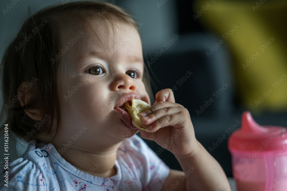 One girl small caucasian child sitting at the table at home alone eat having breakfast or lunch meal pastry alone in day real people growing up development concept copy space