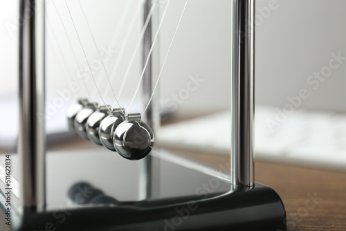 Newton s cradle on wooden table  closeup. Physics law of energy conservation