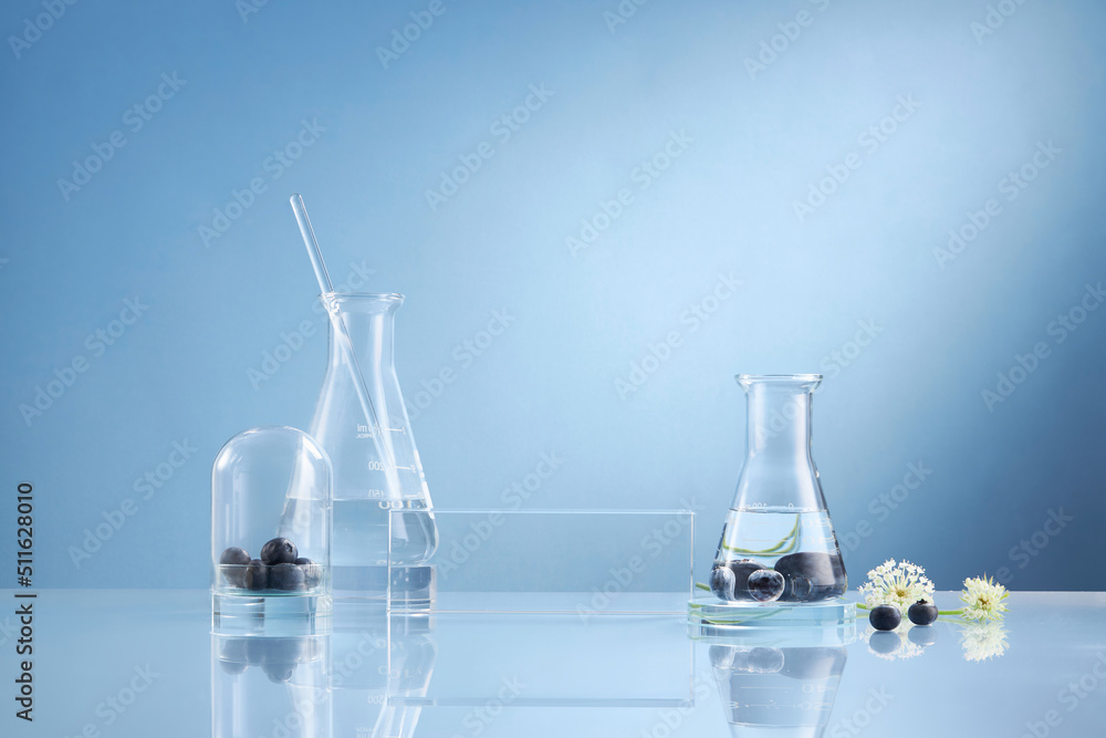 Front view of blueberry extract decorated with transparent podium and glassware blank space in blue background Front view of blueberry extract decorated with transparent podium and glassware blank space in blue background
