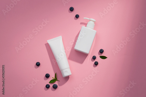 Top view of blueberry extract with transparent podium and cosmetic jar in pink background 
