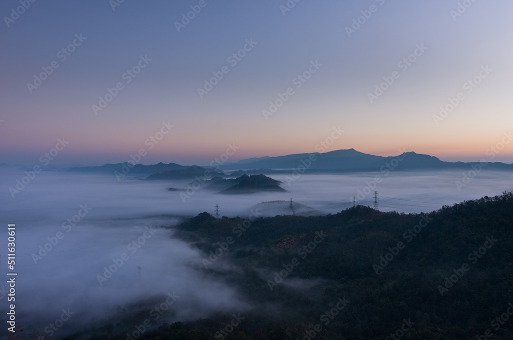 Aerial view Transmission tower in green forest and beautiful morning smooth fog. Energy and environment concept. High voltage power poles. Pang Puay, Mae Moh, Lampang, Thailand. Aerial view Transmission tower in green forest and beautiful morning smooth fog. Energy and environment concept. High voltage power poles. Pang Puay, Mae Moh, Lampang, Thailand.