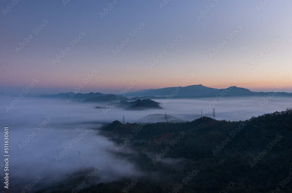 Aerial view Transmission tower in green forest and beautiful morning smooth fog. Energy and environment concept. High voltage power poles. Pang Puay, Mae Moh, Lampang, Thailand.