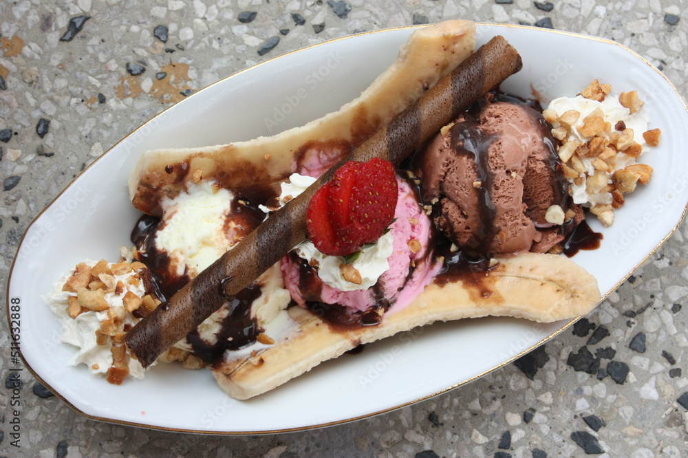 Banana split ice cream on wood table. Homemade Banana Split Sundae with Chocolate Vanilla. Topped with mashed peanuts and cherries. Top view Banana split ice cream on wood table. Homemade Banana Split Sundae with Chocolate Vanilla. Topped with mashed peanuts and cherries. Top view