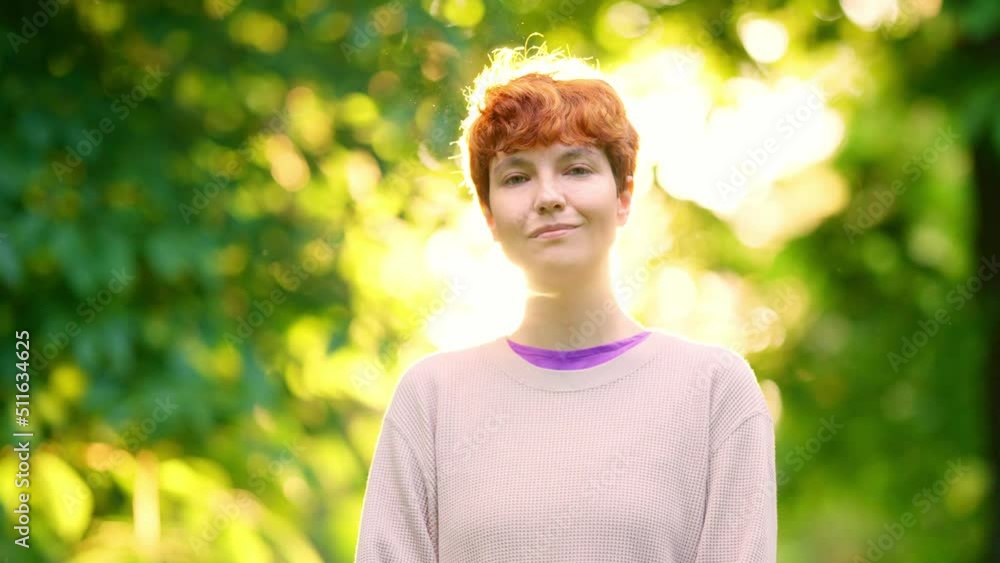 Non-binary person smiling at camera in backlighting outdoors Non-binary person smiling at camera in backlighting outdoors