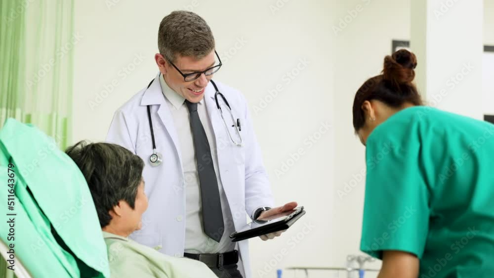 Senior Male doctor professors holding clipboard giving advice to treat patients with general woman doctor in modern hospital ward. Healthcare medical and medicine Senior Male doctor professors holding clipboard giving advice to treat patients with general woman doctor in modern hospital ward. Healthcare medical and medicine
