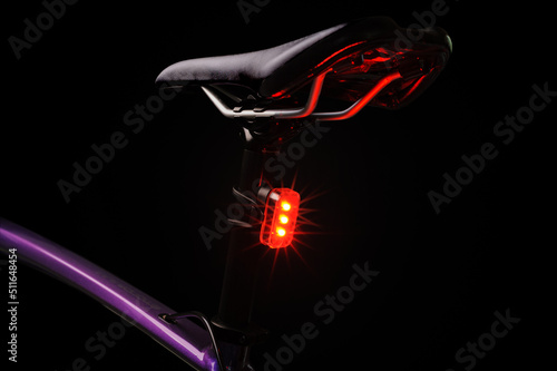 Close-up of illuminated bicycle tail light. Red bicycle tail light