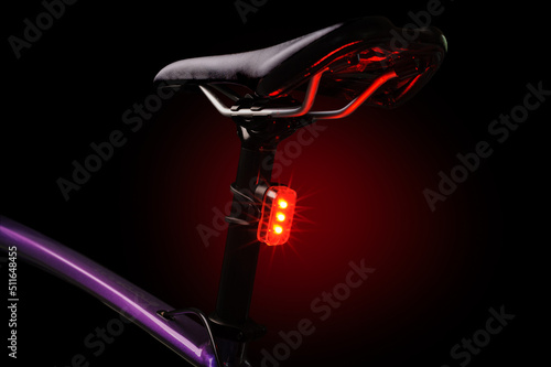 Close-up of illuminated bicycle tail light. Red bicycle tail light