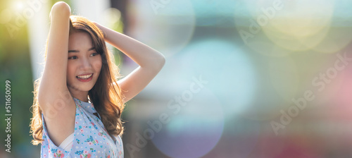 Young Asian woman raise hands isolate on colorful bokeh background.