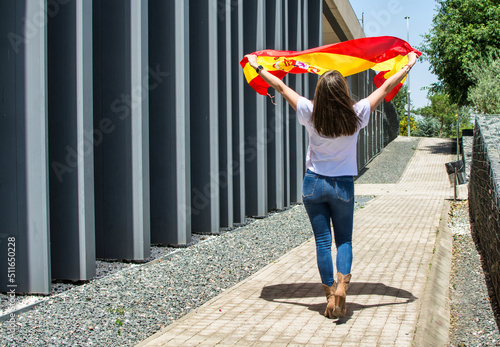 Rear view of a young woman walking with the flag of Spain. Image with copy space