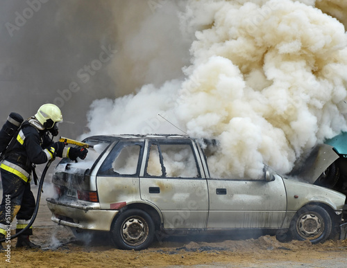 Firefighter works next to a smoking car wreck after a traffic acciden