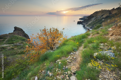 Footpath in mountains above the sea at sunset