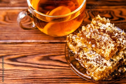 honey in honeycombs and a mug of tea on a brown wooden background 