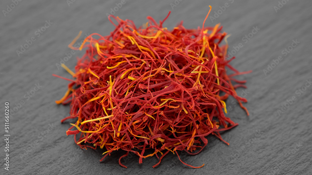 Naklejka premium Saffron threads spice isolated on dark stone plate