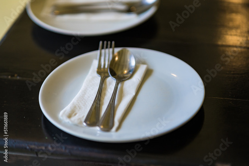 silver spoon and fork with white dish on wooden background.