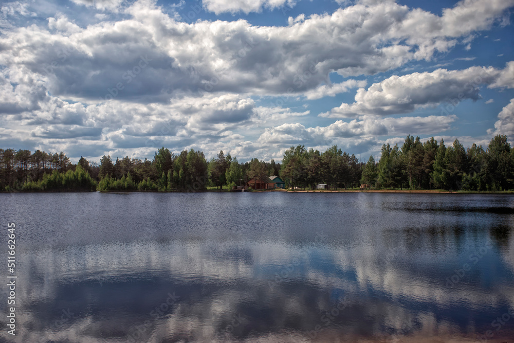 Clouds over a beautiful lake. Beautiful reflection of clouds in the surface of the water. Bright midday sun