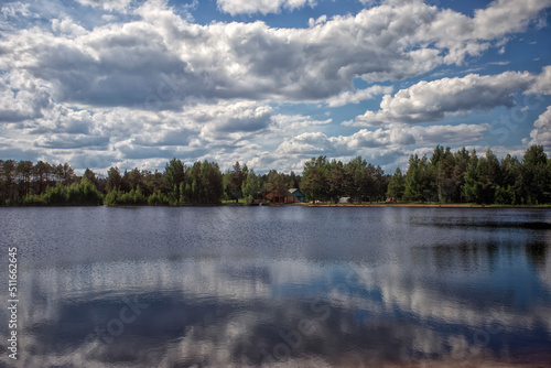 Clouds over a beautiful lake. Beautiful reflection of clouds in the surface of the water. Bright midday sun © Roman