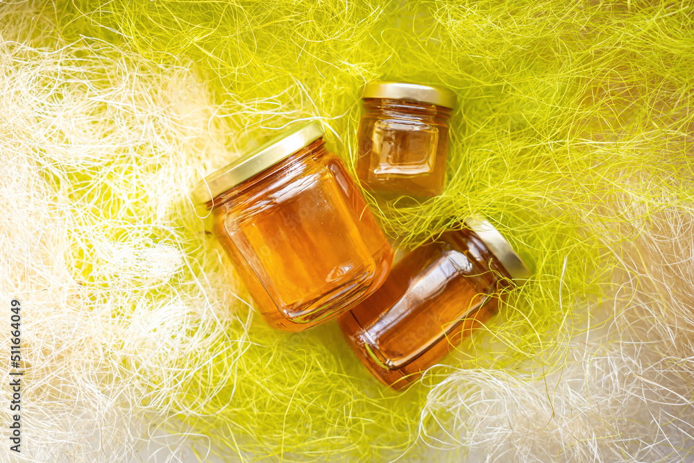 Fototapeta premium Honey in glass jars with flowers background.
