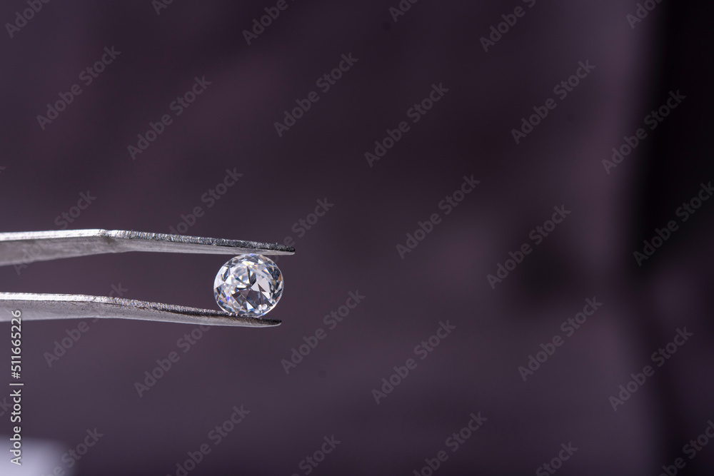Close up of hands of jeweller with magnifying and round cut diamond on dark background with copy space. Close up of hands of jeweller with magnifying and round cut diamond on dark background with copy space.
