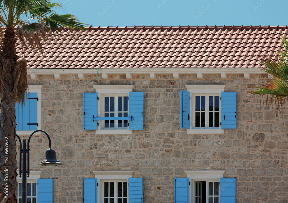 Facade of a old mediterranean building with windows decorated with blue shutters. Croatia