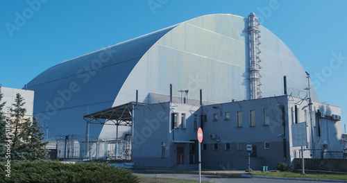 Sarcophagus over the destroyed reactor of the Chernobyl nuclear power plant. Giant metal hangar, radiation protection. No people, windy weather.