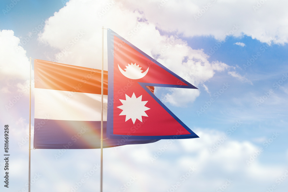 Fototapeta premium Sunny blue sky and flags of nepal and netherlands