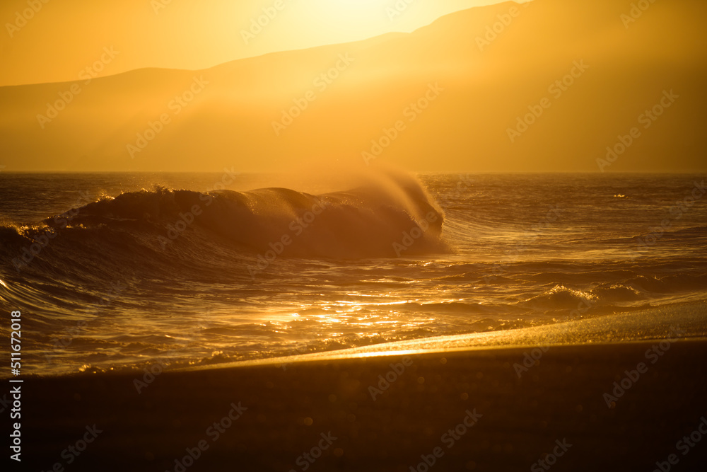 Gold sky and sea water. Beach sunrise over the tropical sea. Colorful sunset with wave splashes on the beach. Waves splashes.