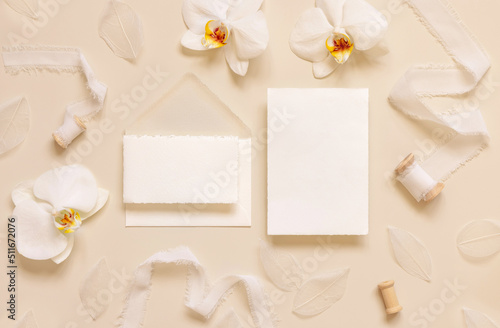 Wedding cards near white orchid flowers and silk ribbons on light yellow  suite mockup