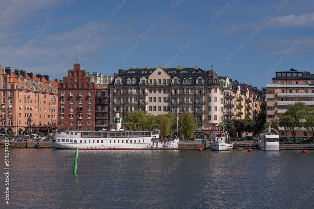 Apartment houses at the waterfront, a pier with old steam boat on the island Kungsholmen a sunny summer day in Stockholm