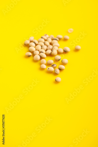 Dry soybean seed on yellow background.