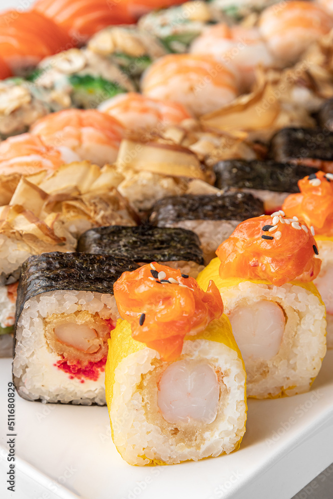 set of different colorful maki sushi rolls with tuna, salmon, shrimp, crab and avocado and green bamboo leaf in a white ceramic plate with chopstick on a bright marble background, side view, close-up set of different colorful maki sushi rolls with tuna, salmon, shrimp, crab and avocado and green bamboo leaf in a white ceramic plate with chopstick on a bright marble background, side view, close-up