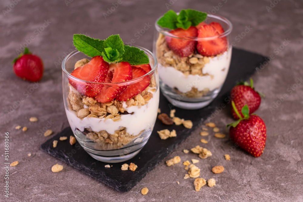 Strawberry parfait in a glass with yogurt and granola on a gray background. Strawberry parfait in a glass with yogurt and granola on a gray background.