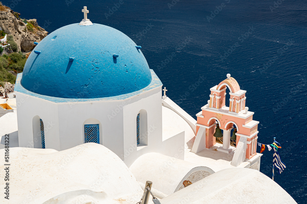 Blue church dome and pink bell tower in Oia on Santorini island