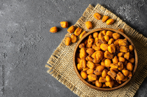 Roasted salted Corn Nuts with Spice and Sauce in bowl on dark rustic table, Nut concept photo