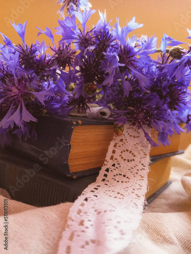 wedding bouquet of purple cornflowers with white vintage ribbon with blue books, boxes side view