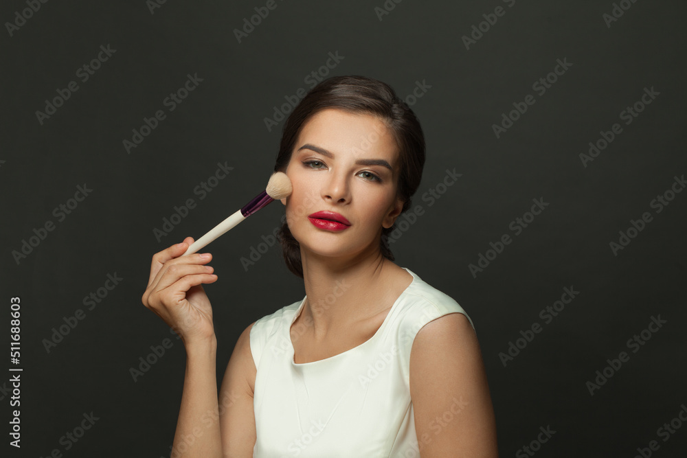 Obraz premium Beauty Face. Portrait of beautiful model applying blush with cosmetic brush. Young woman with soft smooth skin and fresh makeup. Skin cosmetics.