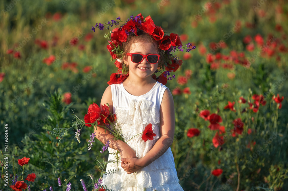 Happy little girl on a summer walk in a field with poppies