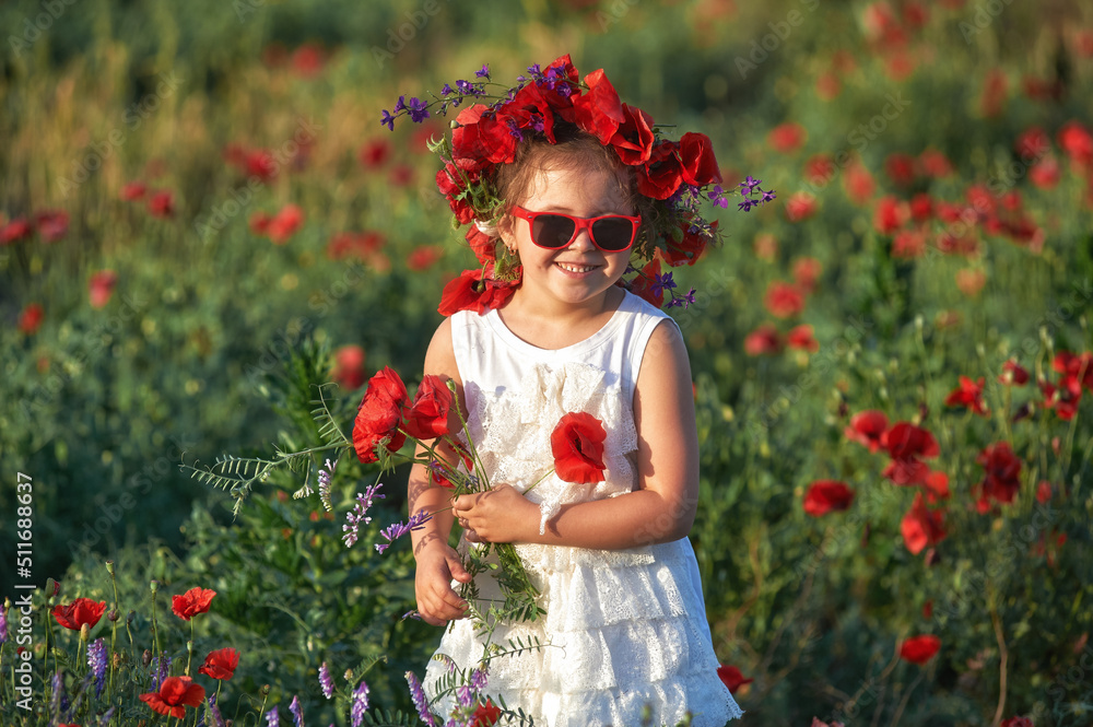 Happy little girl on a summer walk in a field with poppies
