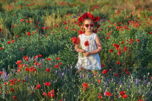 Obraz na płótnie Happy little girl on a summer walk in a field with poppies w salonie
