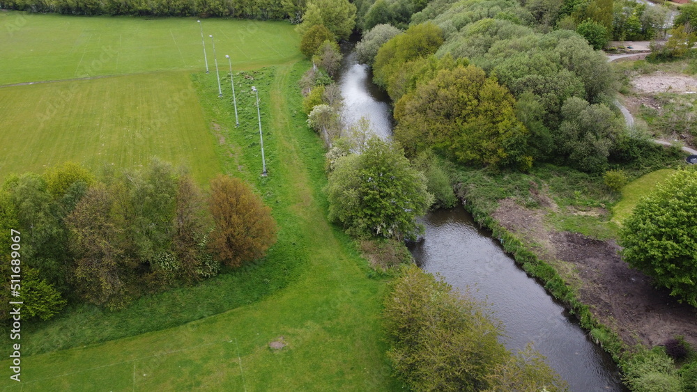 Aerial view looking down onto a river surrounded by large trees and green farmland. Aerial view looking down onto a river surrounded by large trees and green farmland.