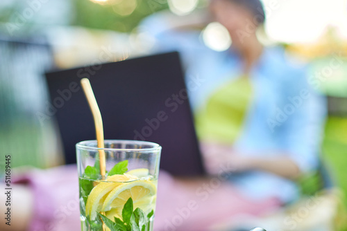 Summer citrus lemonade with reusable metal straws, Woman using typing