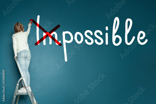 Child girl with impossible inscription on blue chalkboard background. Success, develop and motivation concept photo