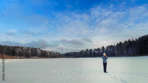 Young woman takes a picture on a smartphone in the middle of a frozen lake