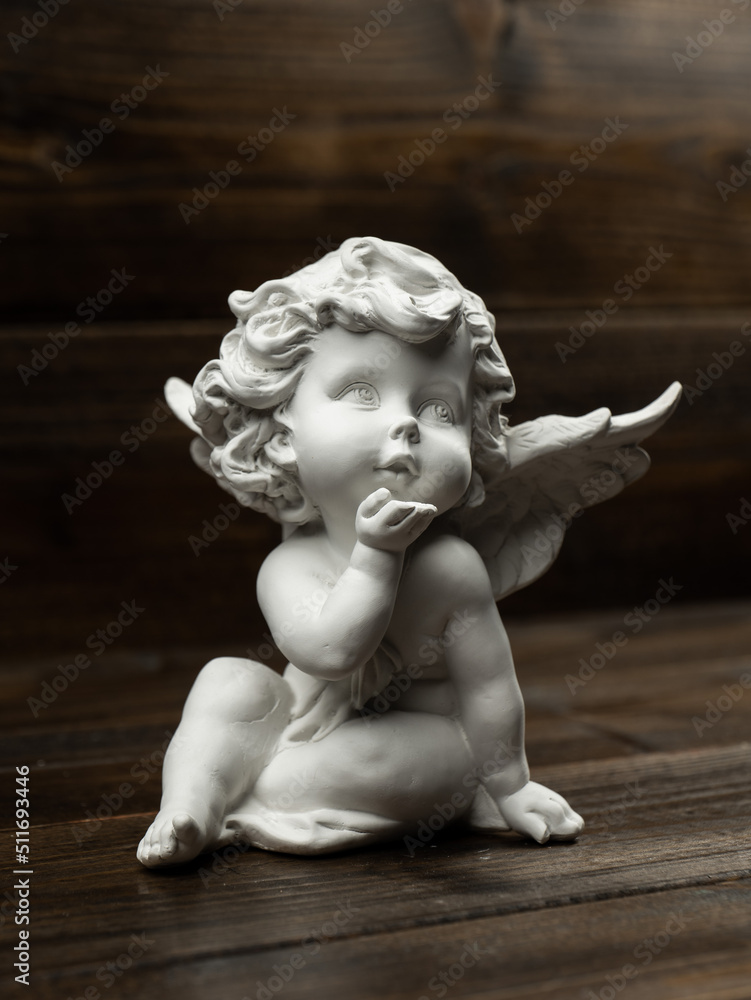 plaster white statuette in the form of an angel on a dark wooden background plaster white statuette in the form of an angel on a dark wooden background