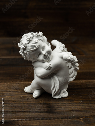 plaster white statuette in the form of an angel on a dark wooden background