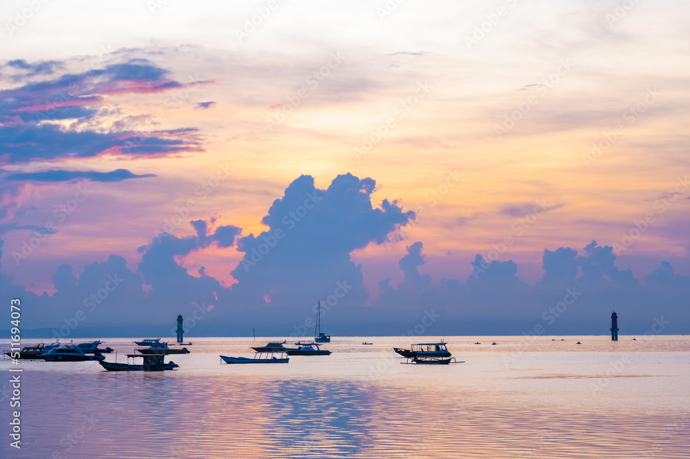 Sunrise over boats in silhouette on ocean in Bali
