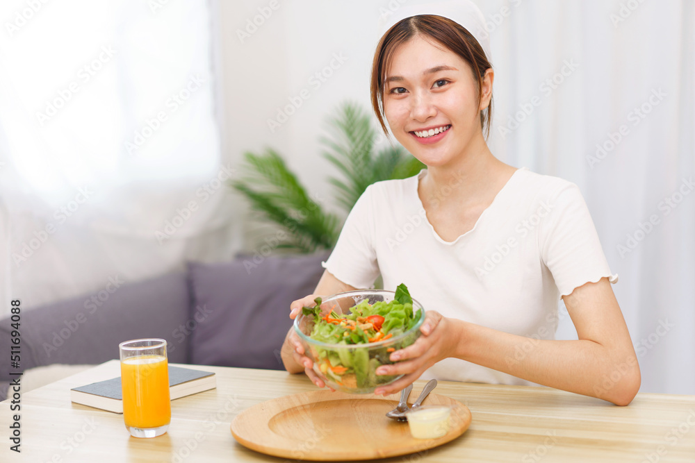 Lifestyle in living room concept, Young Asian woman smiling and holding bowl of vegetable salad