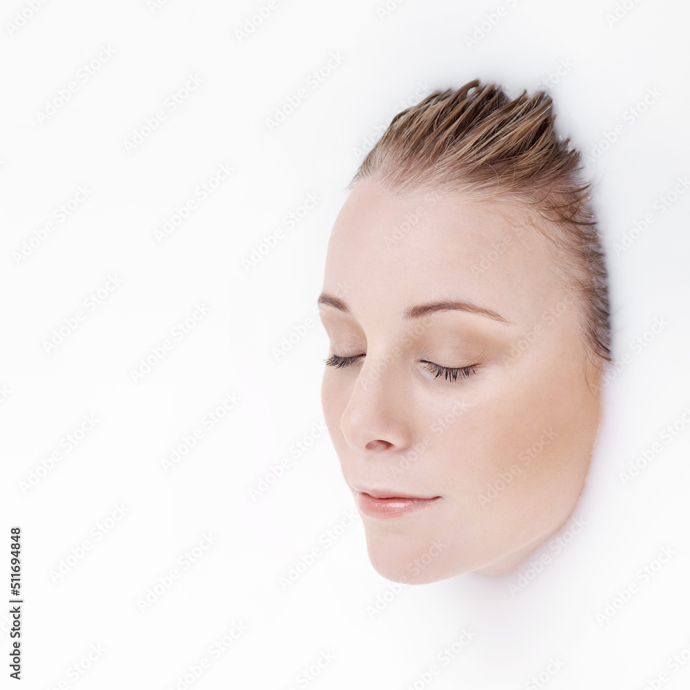 Totally immersive beauty. Studio shot of an attractive womans face emerging from a white liquid. Totally immersive beauty. Studio shot of an attractive womans face emerging from a white liquid.