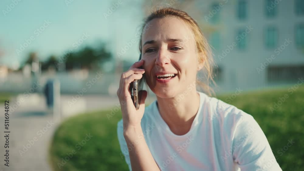 Close up blond woman looking happy talking over smartphone while waiting beginning of workout in the city park. Distant communication Close up blond woman looking happy talking over smartphone while waiting beginning of workout in the city park. Distant communication