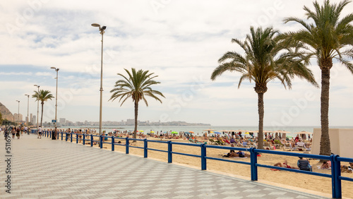 People on the beach and in the water at Alicante, Spain, in June 2022, on a bright sunny day. 