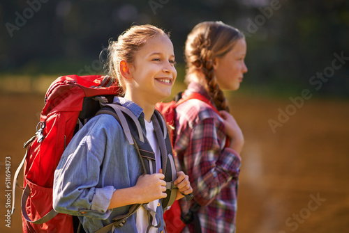 Carefree in nature. Shot of two young girls wearing backpacks walking together.